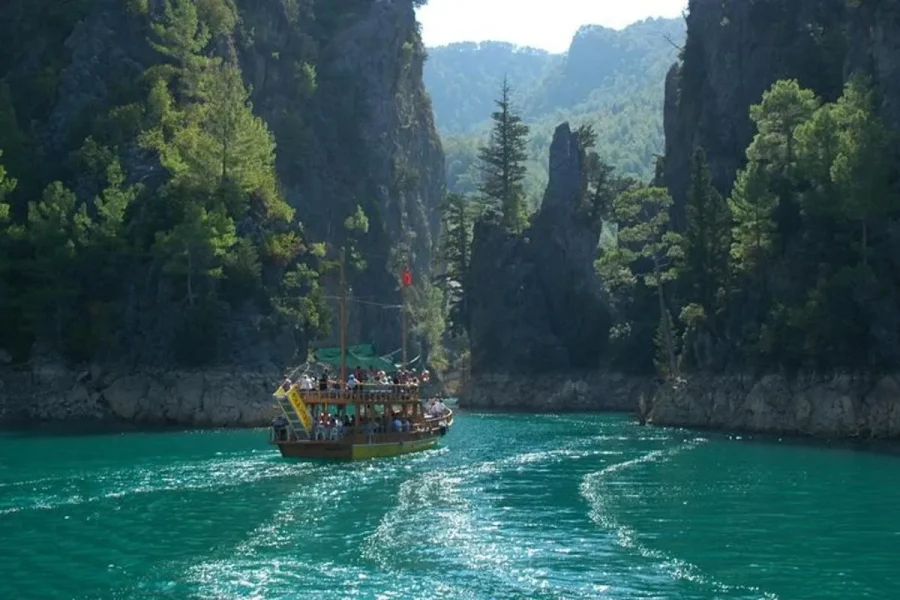 Scenic view of Green Canyon from the boat during a tour from Antalya Description: Calm emerald waters surrounded by lush forested hills captured from the boat deck.