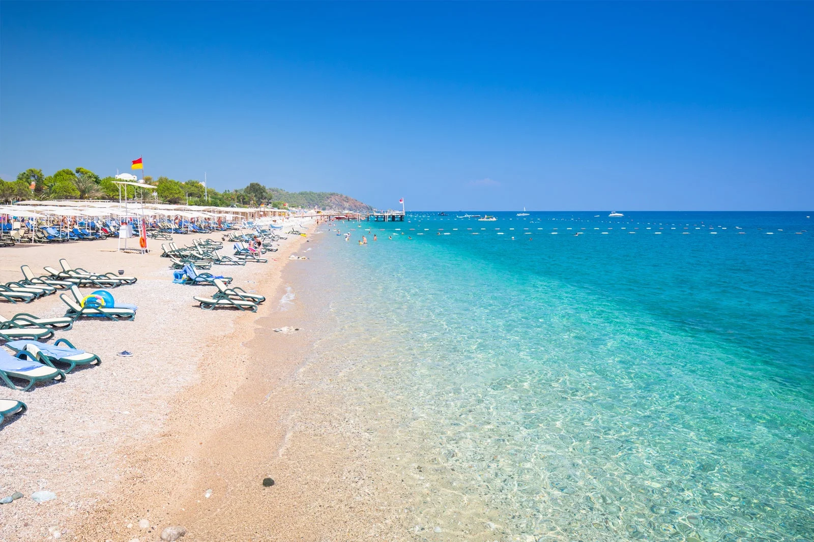 Turquoise sea and sunbeds lined up on a peaceful beach in Kemer, Antalya